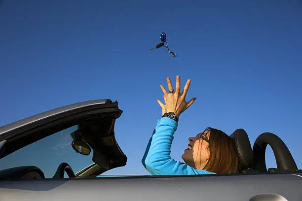 a woman throwing car jey ring in the air